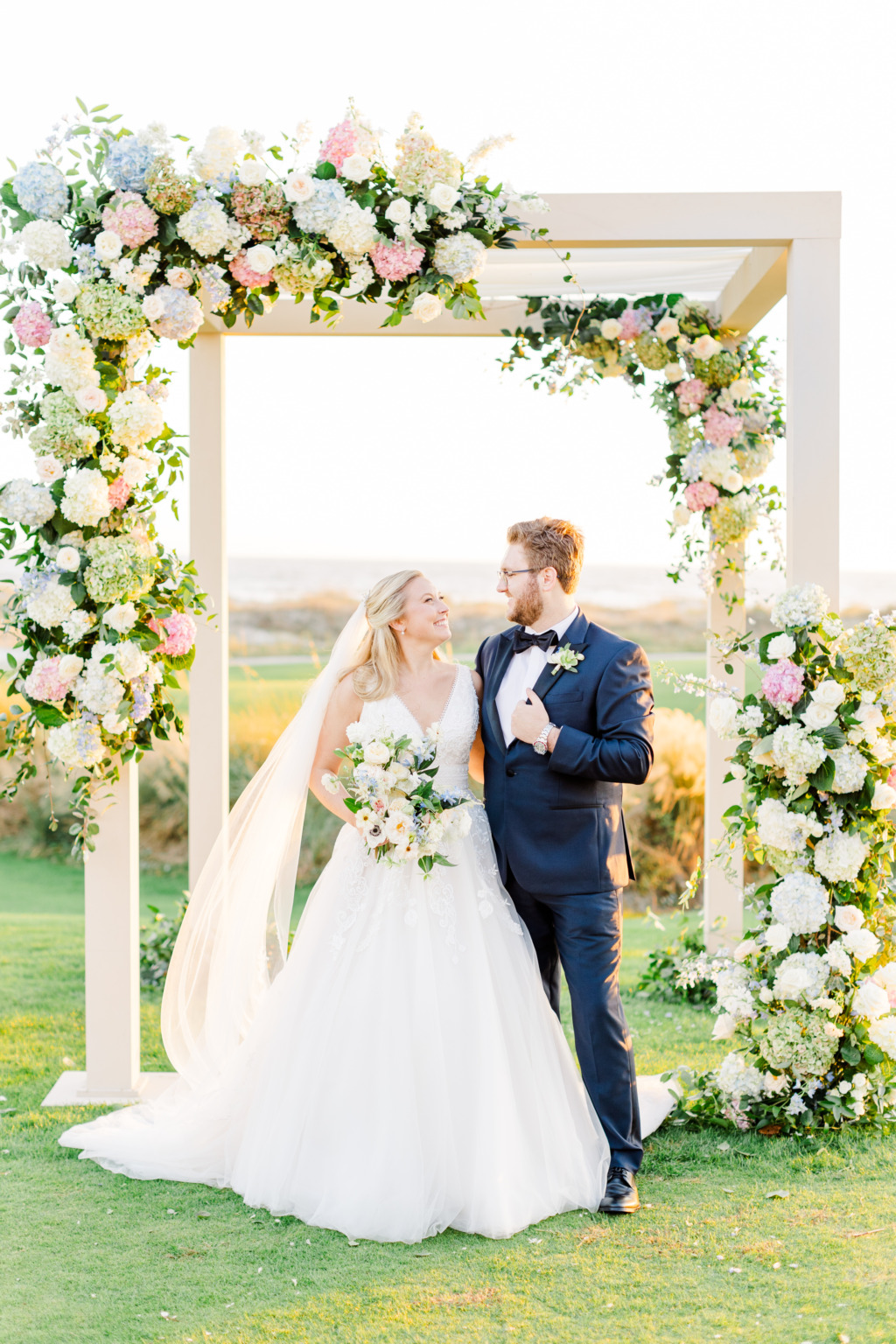 Bride and groom kiss under flower bed alter